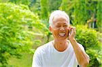 Healthy senior Asian man on the phone outdoor green park
