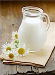 pitcher of milk on a wooden table wish  daisy , rustic still life