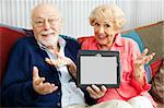 Confused senior couple holding their new tablet PC.  Blank computer screen ready for your text.