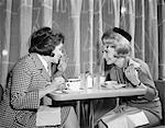 1960s TWO WOMEN GOSSIPING AT LUNCH IN RESTAURANT