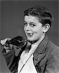 1930s 1940s PORTRAIT OF BOY WITH NAPKIN BIB HOLDING ROAST TURKEY LEG SMILING LOOKING AT CAMERA