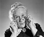 1950s PORTRAIT OF SMILING OLD LADY HOLDING HER ANTIQUE WIRE FRAME GLASSES