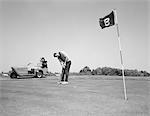 1960s MAN PLAYING GOLF PUTTING GOLF BALL TOWARDS FLAG AND CUP HOLE ON 9TH GREEN SPRING SUMMER OUTDOOR