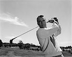 1960s MAN PLAYING GOLF TEEING-OFF GOLF BALL FROM TEE WITH DRIVER OUTDOOR