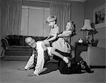 1950s 1960s DAD CARRYING BOY & GIRL PIGGYBACK ON LIVING ROOM FLOOR