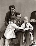 1930s FATHER READING BOOK TO DAUGHTER & SON WITH MOTHER LOOKING OVER HIS SHOULDER