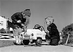 ANNÉES 1950 BOY ET GIRL AT JOUER JOUET DE RÉPARATION DE VOITURE