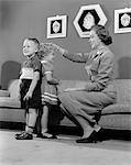 1950s MOTHER MEASURING DIFFERENCE IN HEIGHT BETWEEN SON AND DAUGHTER INDOOR