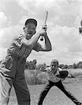 1950s GRANDFATHER AT BAT WITH BOY AS CATCHER PLAYING BASEBALL