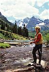 1990s MATURE WOMAN FLY FISHING MOUNTAIN STREAM
