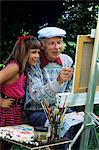 1980s 1990s GRANDDAUGHTER WATCHING GRANDFATHER PAINT AT EASEL