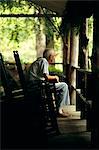 1980s ELDERLY SENIOR MAN SITTING ON PORCH IN ROCKING CHAIR