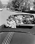 1950s PORTRAIT WELL DRESSED FAMILY MOM DAD SON DAUGHTER IN CONVERTIBLE CAR TOP DOWN LOOKING AT CAMERA OVER BACK OF TRUNK