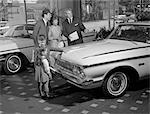 1960s FAMILY OF 4 IN AUTO SHOWROOM WITH SALESMAN LOOKING AT WHITE PLYMOUTH