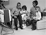 1960s BLACK FAMILY WATCHING PORTABLE TELEVISION