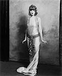 1920s WOMAN WEARING EXOTIC EGYPTIAN INSPIRED LAME GOWN COSTUME WITH JEWELED BELT HEADPIECE FASHION