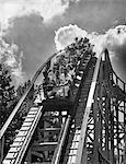 1950s GROUP OF TEENS ON ROLLER COASTER COMING DOWN TOP OF CREST OUTDOOR