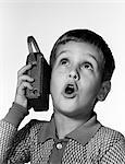 1960s BOY HOLDING TRANSISTOR RADIO UP TO HIS EAR WHILE HE SINGS ALONG