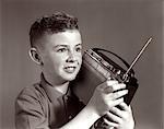 BOY DES ANNÉES 1960 À L'ÉCOUTE DE RADIO PORTABLE INTÉRIEUR