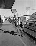 1950s BUSINESSMAN WITH BRIEFCASE IN AIR RUNNING AFTER DEPARTING TRAIN