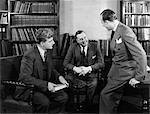 1940s GROUP OF THREE BUSINESSMEN SITTING TOGETHER IN LIBRARY TALKING SMILING