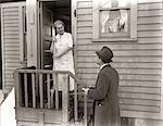 1940s 1930s MAN DOOR-TO-DOOR SALESMAN TALKING WOMAN TO HOUSEWIFE AT BACK DOOR