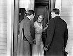 1930s 1940s TWO DOOR-TO-DOOR SALES SALESMEN TALKING TO HOUSEWIFE AT FRONT DOOR MAKING SALES PRESENTATION