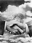 1940s BUSINESSMEN'S HANDS IN HANDSHAKE SUPERIMPOSED ON BACKGROUND OF GLOBE BURIED AMONG CLOUDS