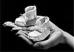 1940s 1950s WOMAN MOTHER HOLDING BABY BOOTIES IN HER HANDS