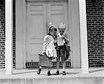1940s LITTLE BOY AND GIRL WITH SCHOOL BAGS LOOKING AT NOTEPAD OUTDOOR