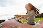 Girl driving toy airplane in field