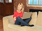 Smiling woman using laptop on sofa