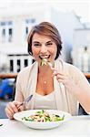 Woman eating at sidewalk cafe