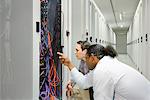 Businessmen examining wires in server