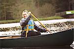 Woman rowing canoe on still lake