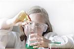 Girl pouring liquid into beakers