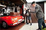 Grandfather and grandson packing vintage car with trunk suitcases in garage