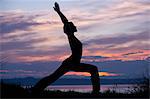 Silhouette der Frau in Krieger Yoga-Pose bei Sonnenuntergang