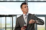 Businessman with airplane ticket and passport checking watch