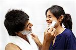 Man applying shaving cream on woman's face