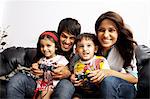 Porträt von Eltern mit ihren Kindern sitzen und spielen Videospiel