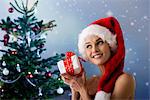 Woman wearing Santa hat, shaking Christmas gift