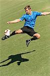 Joueur de soccer botter le ballon dans les airs.