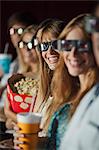 Audience wearing 3-D glasses in movie theater, smiling at camera