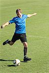 Soccer player kicking soccer ball on soccer field