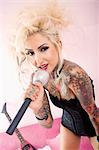 Portrait d'une femme blonde tatouée chante avec microphone