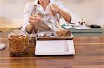 Close-up of a female employee measuring spice on weight scale in store