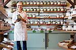 Portrait of a happy senior merchant standing with spice jar in store