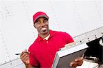 Portrait of a happy African American man holding clipboard with delivery truck in background