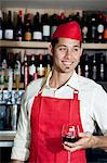 Heureux barman beau tenant le verre de vin en bar